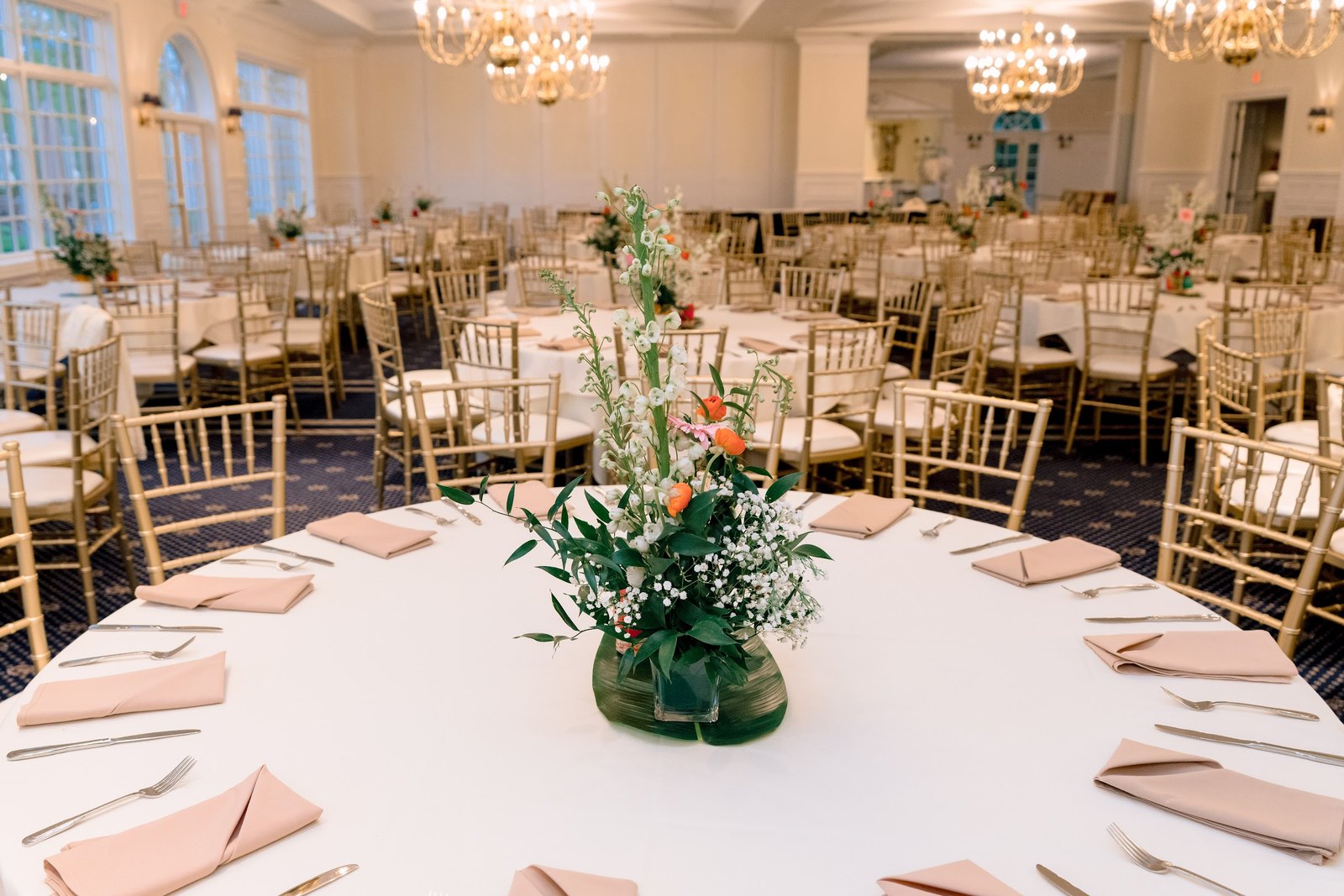 Round table with blush napkins under crystal chandeliers