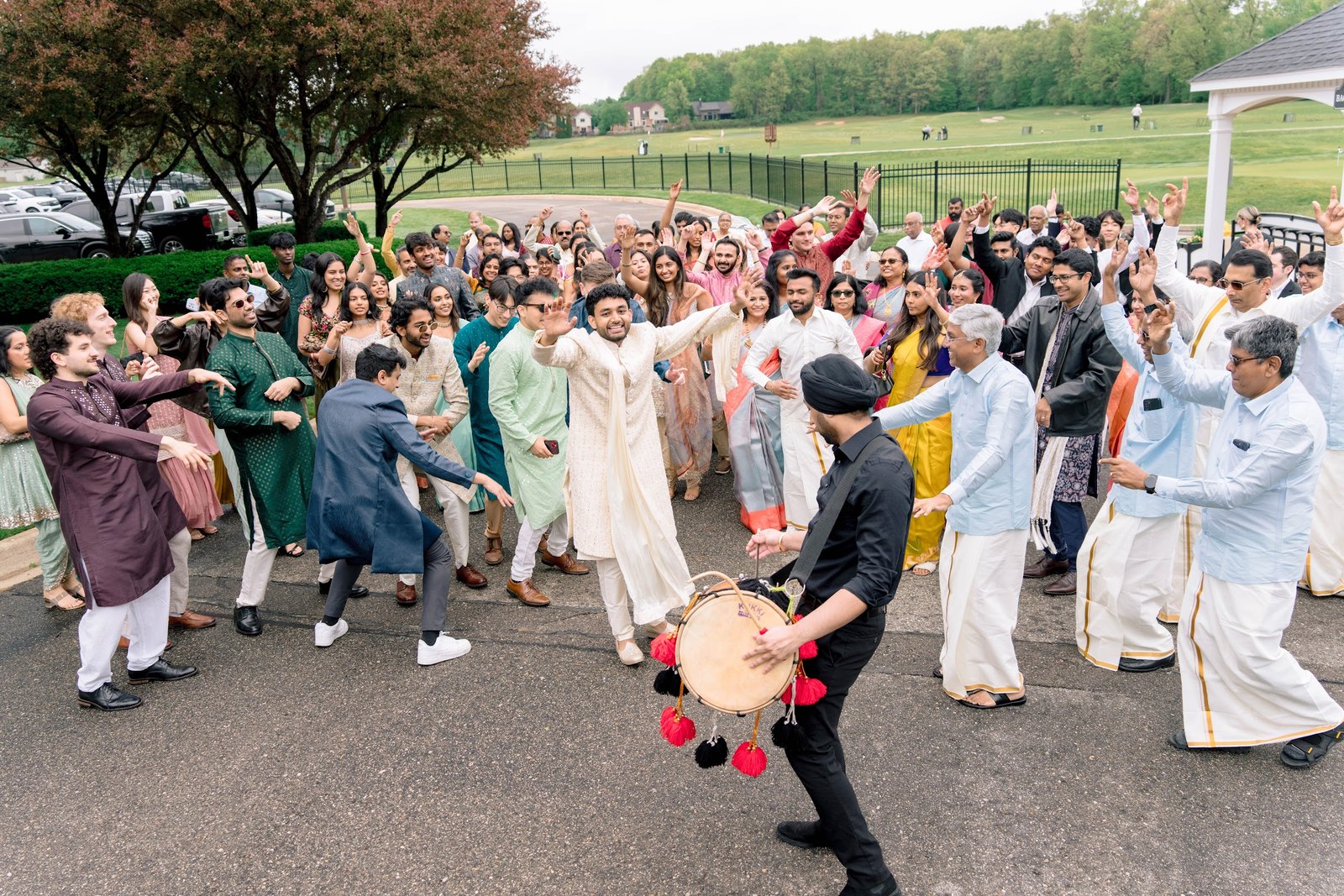 Groom dancing with guests and a dhol player during the baraat