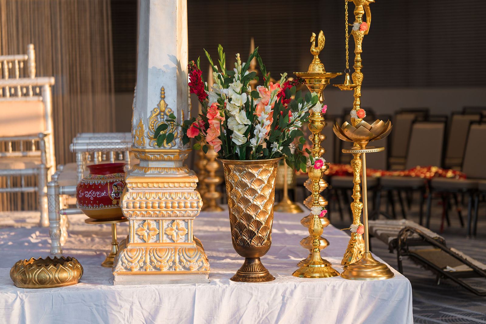 Brass oil lamps beside gold vases of gladiolus and roses