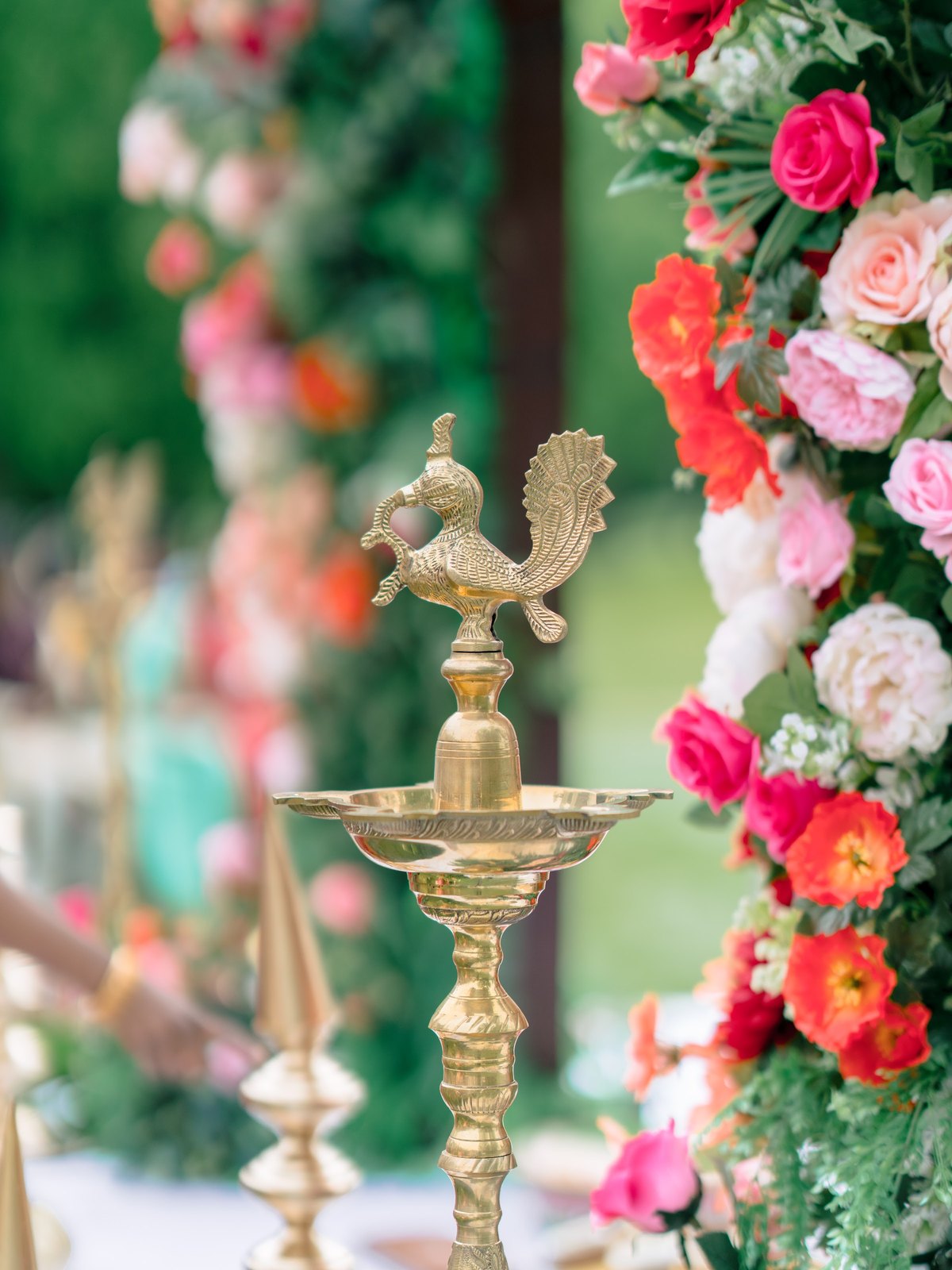 Brass peacock lamp framed by red and pink roses