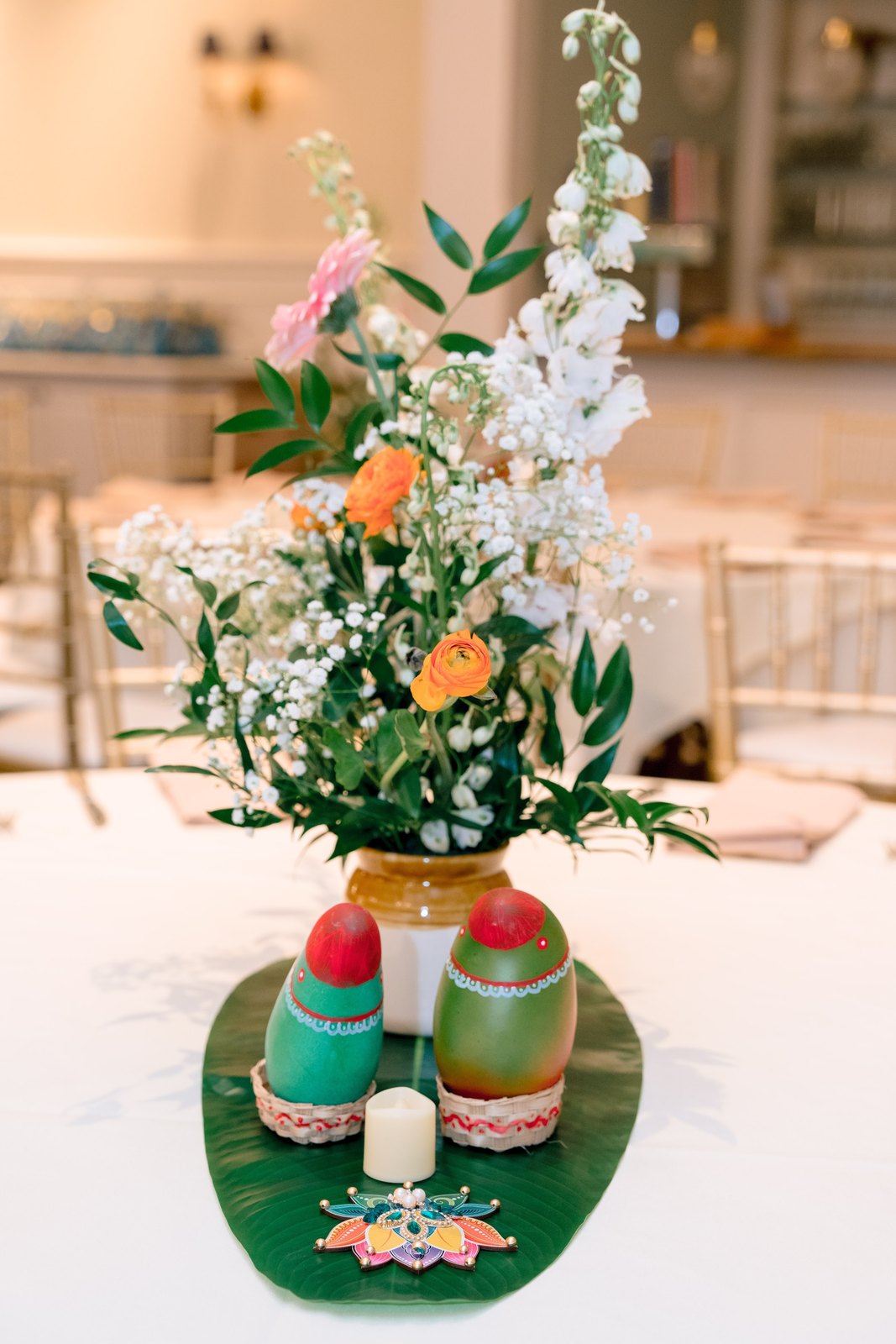 Floral centerpiece with painted coconuts on a banana leaf