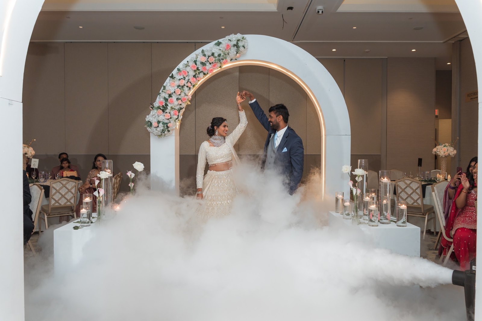 Couple dancing beneath a floral arch with low fog