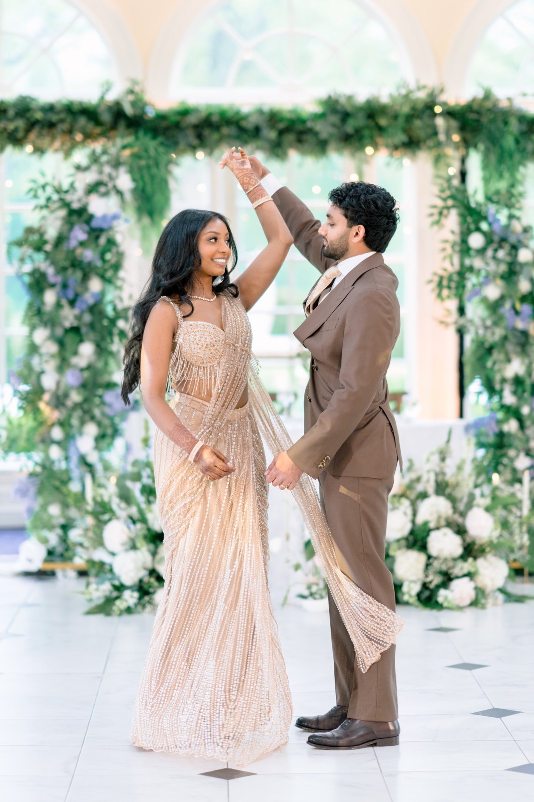 Couple twirling beneath a blue and white floral arch