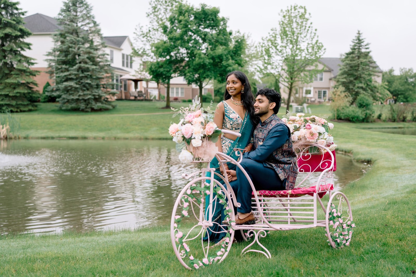 Couple on a flower-covered bicycle beside a pond