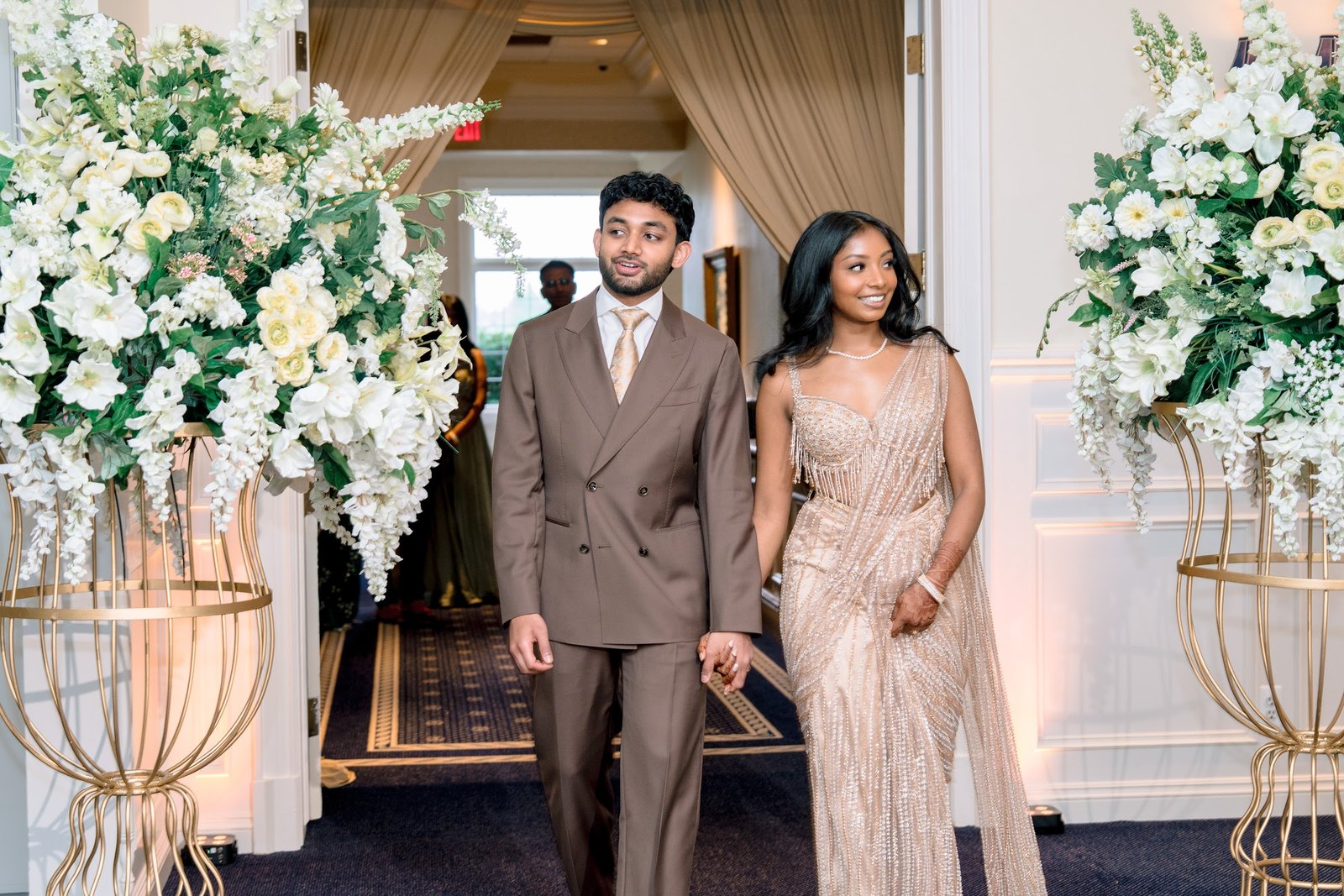 Couple walking in between tall white floral arrangements