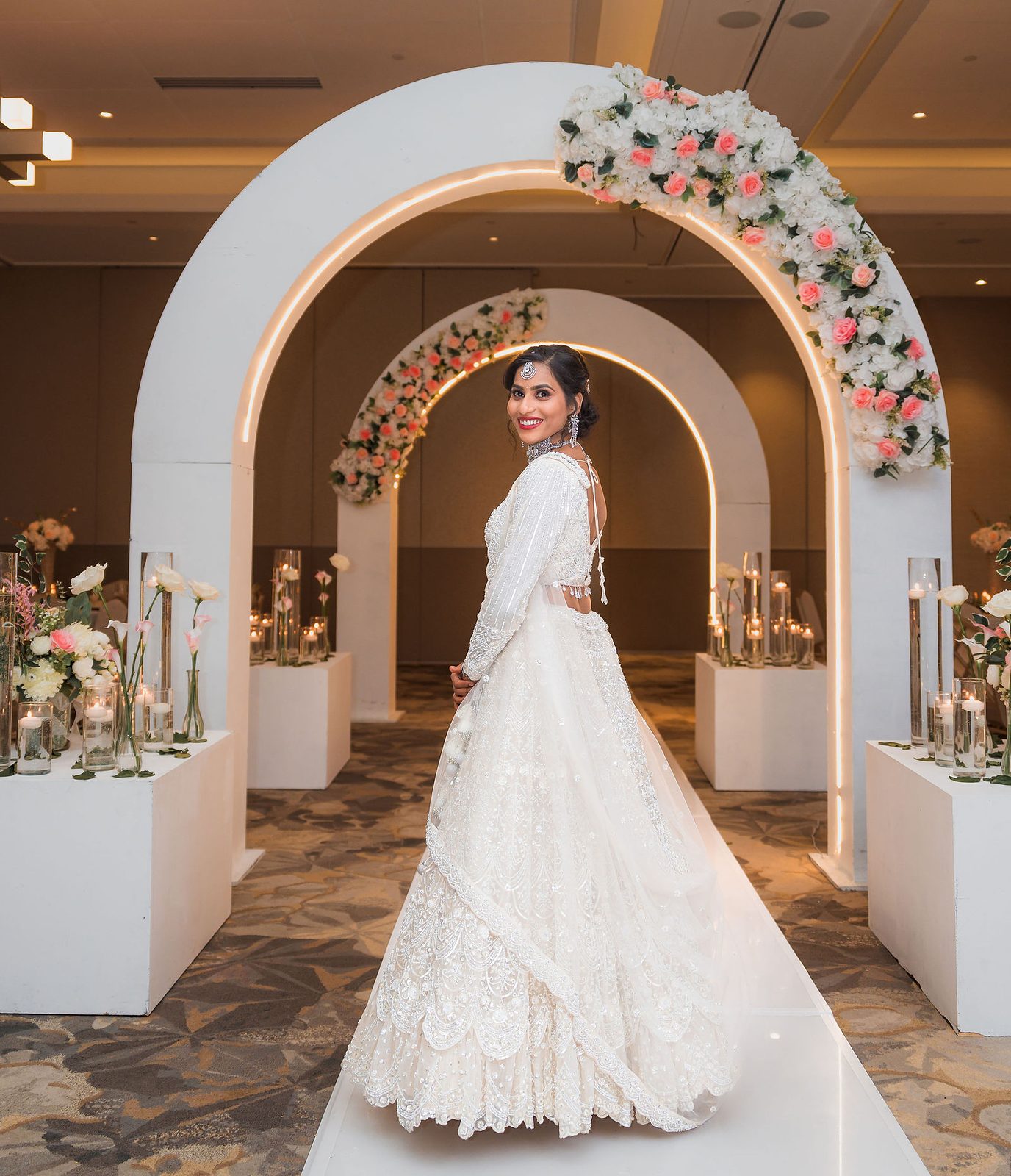 Bride standing beneath a floral white arch