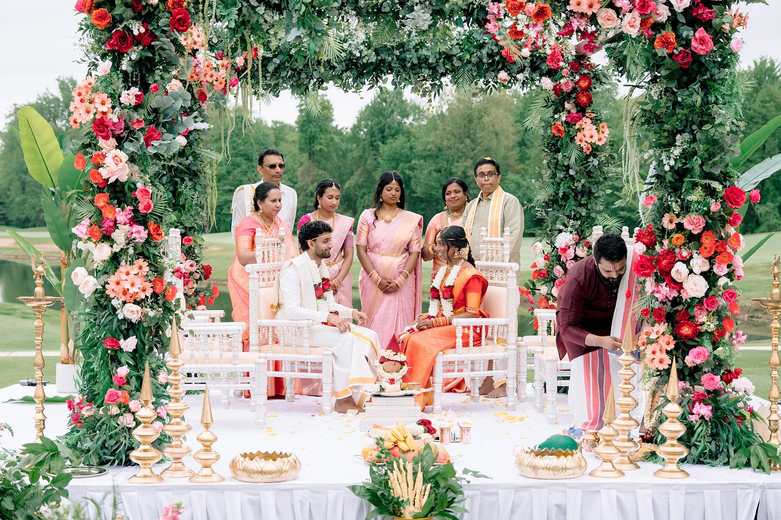Wedding ceremony beneath a floral mandap with family