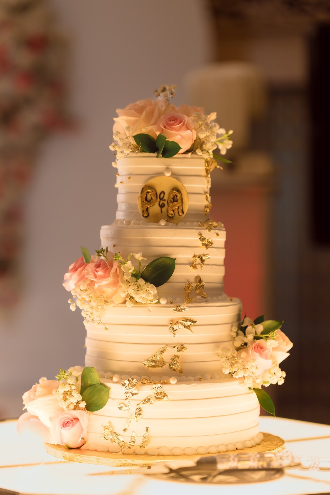 Tiered ivory wedding cake with a monogram and roses