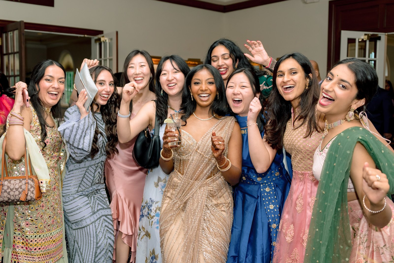 Friends in saris and gowns cheering together
