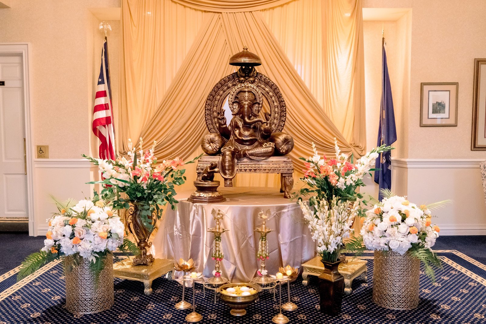 Ganesha idol on a draped gold altar with flowers