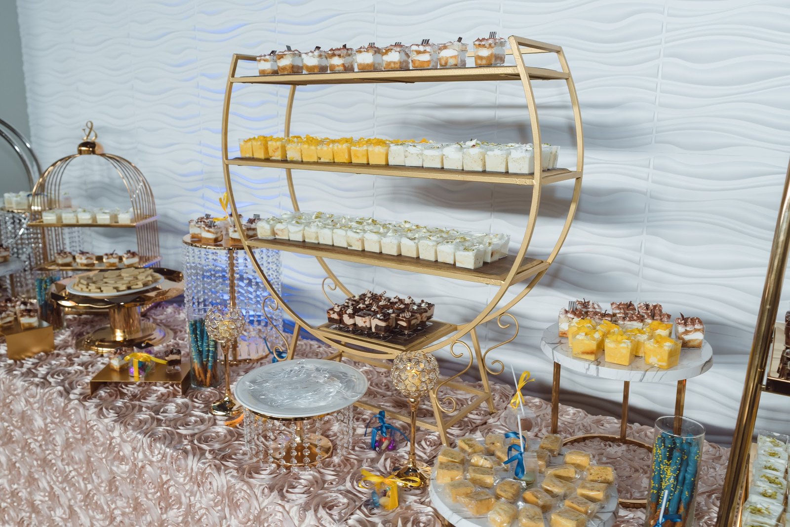 Tiered gold stands of desserts on a rose-textured table