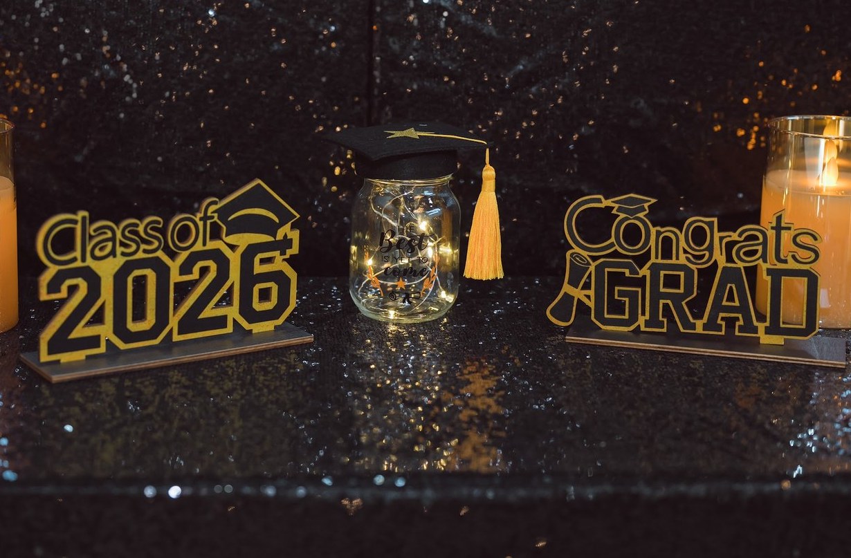 Class of 2026 and Congrats Grad signs between candles at a graduation party