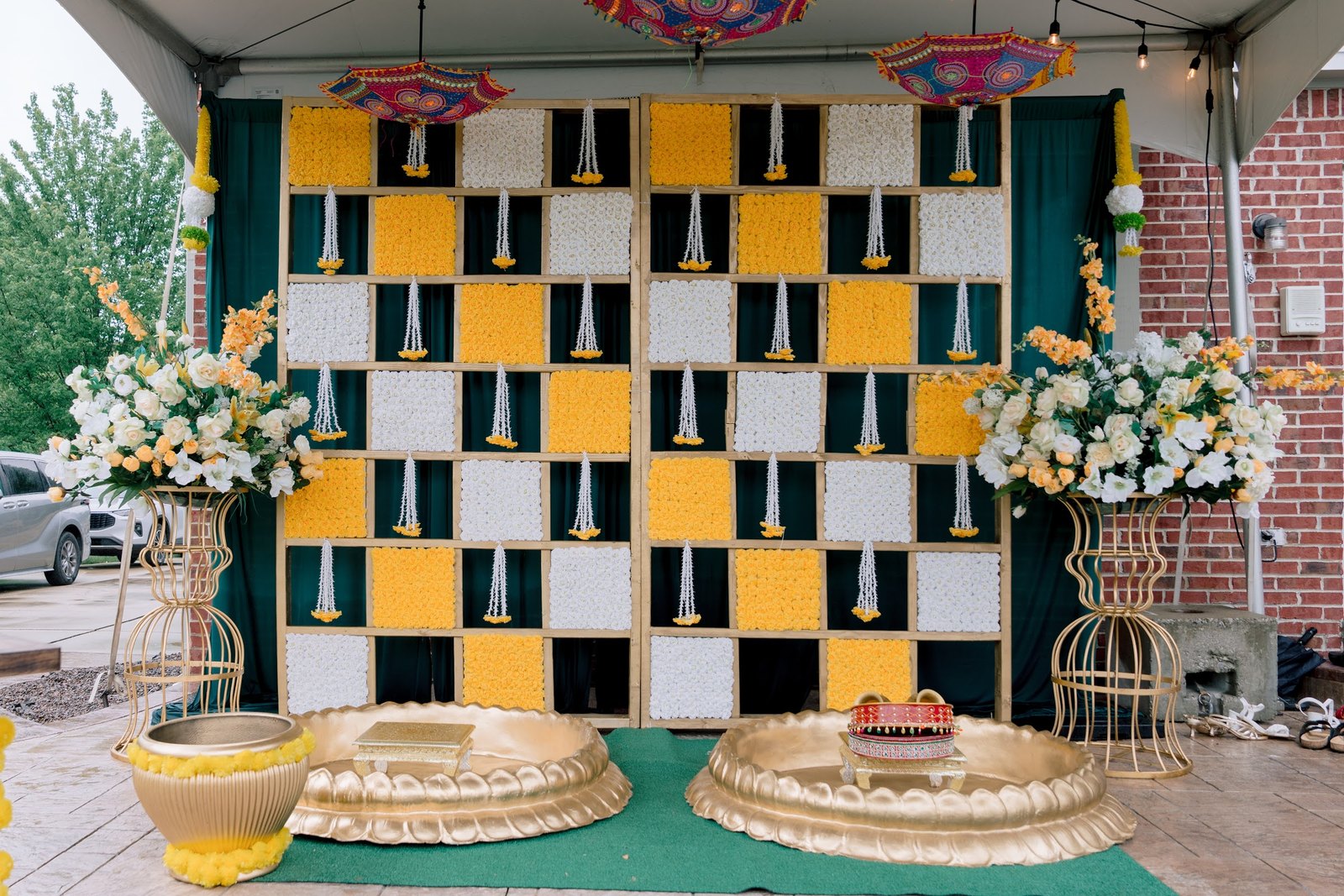 Yellow and green checkered haldi backdrop with brass urns and parasols