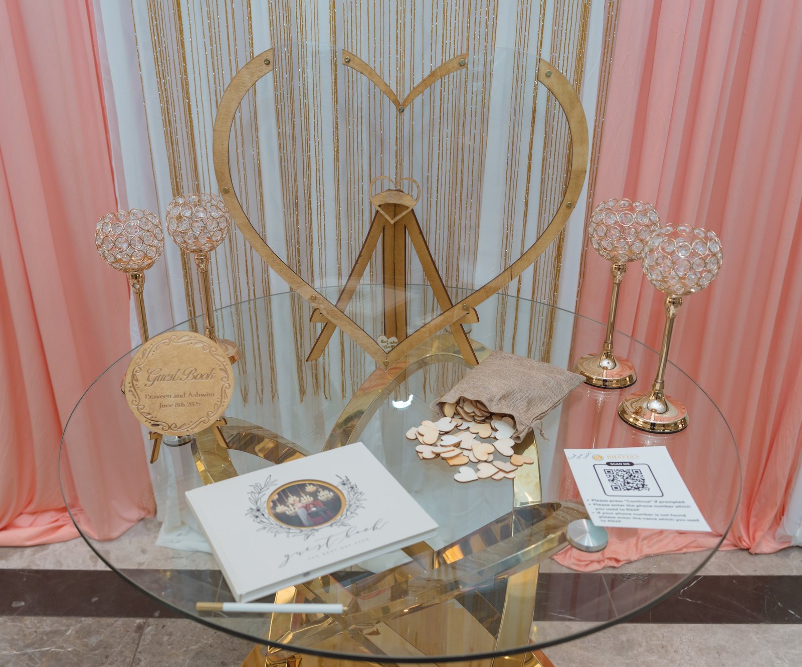 Gold heart sign-in table with crystal candle holders and pink drapes