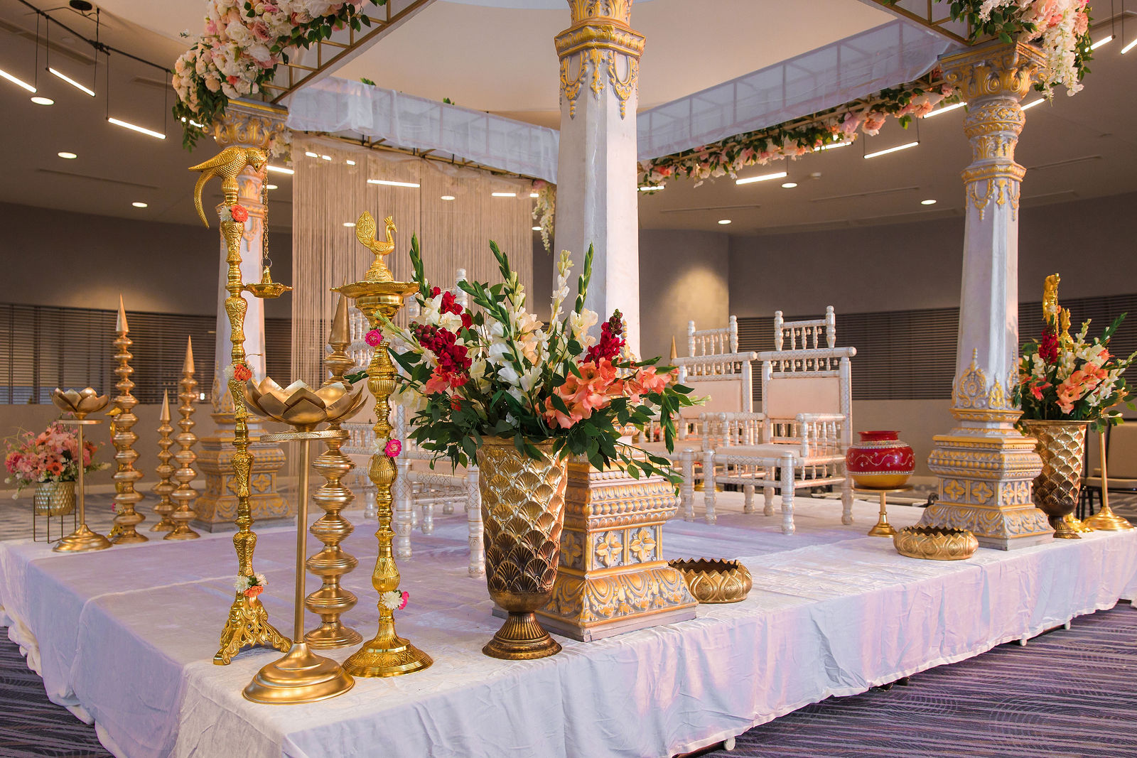 Mandap side view with tall brass lamps and floral arrangements