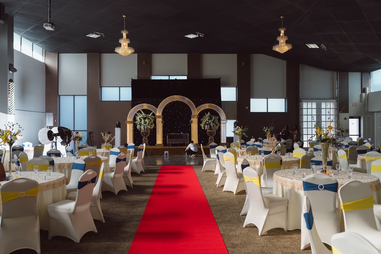Red carpet aisle leading to gold arches in a decorated hall