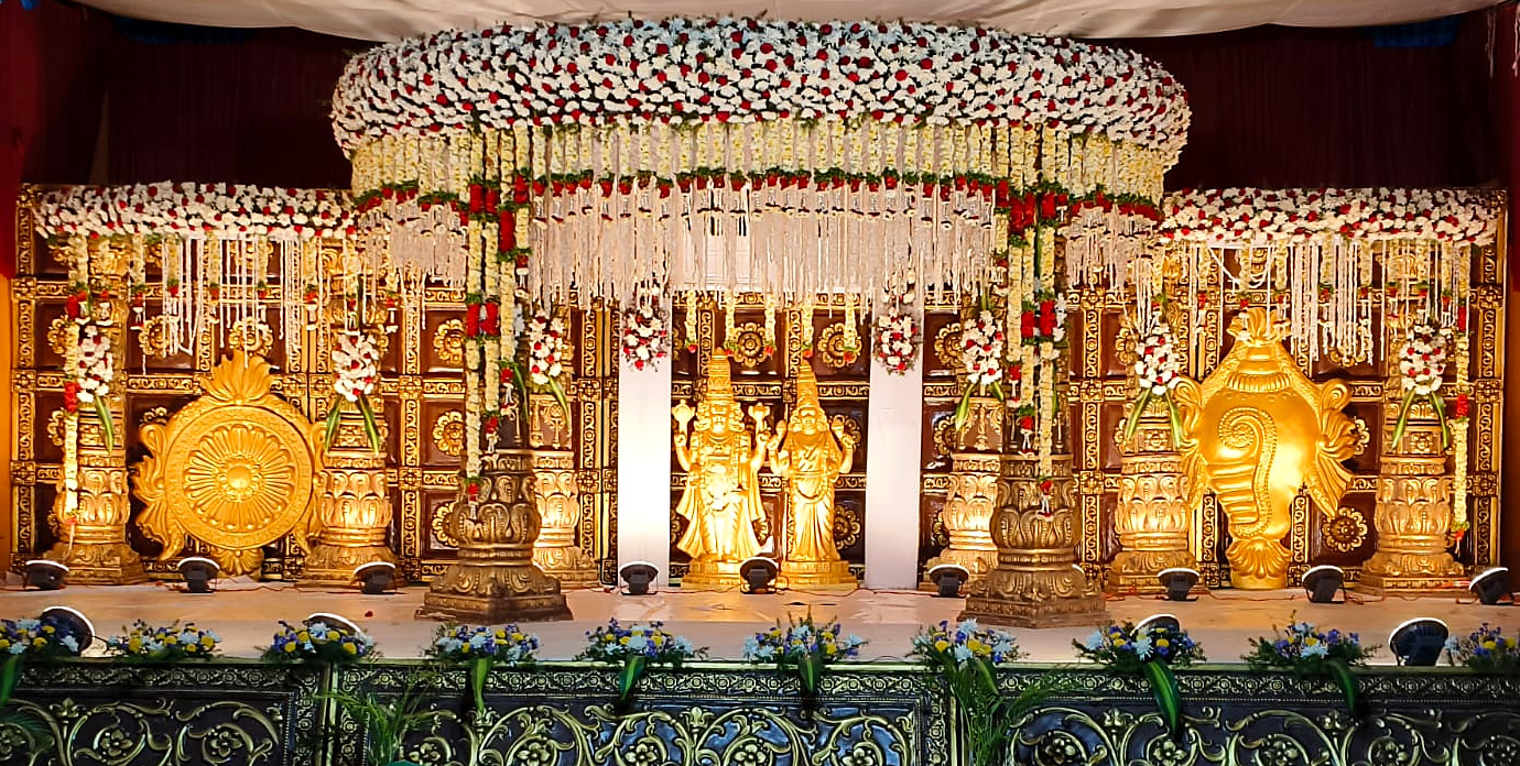 Grand temple-style wedding stage with a jasmine and rose floral canopy, golden deities, chakra and conch